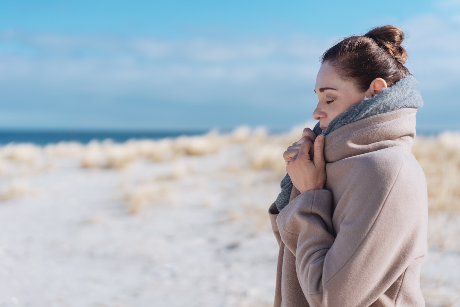 Young woman on a cold sunny beach in winter
